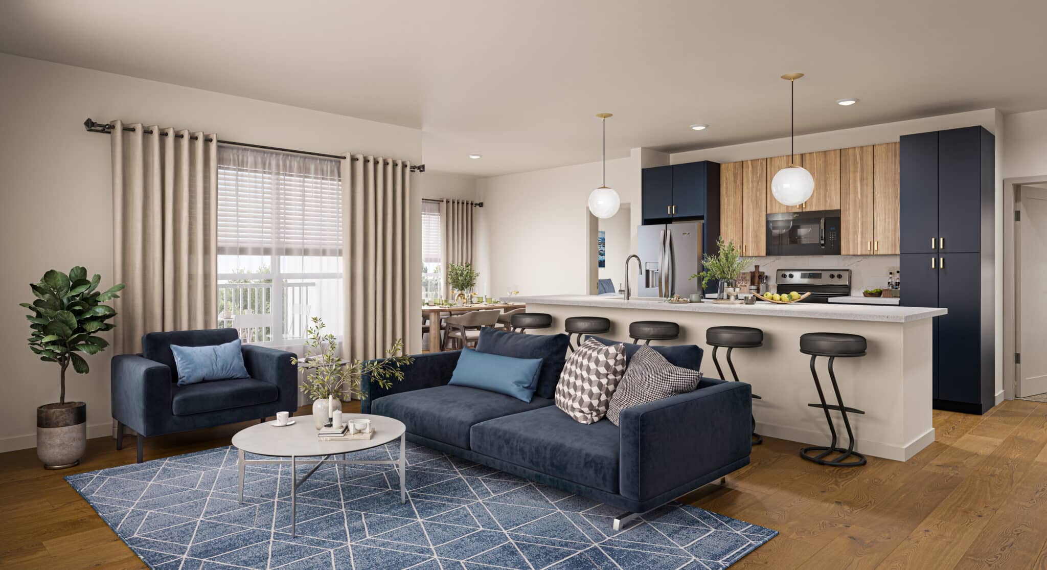 Princeton Wilmington Apartments | Modern open-concept living space with a navy sofa, armchair, patterned rug, round coffee table, kitchen island with barstools, and a kitchen featuring navy and wood cabinets, stainless appliances, and pendant lights. | Wilmington MA Apartments